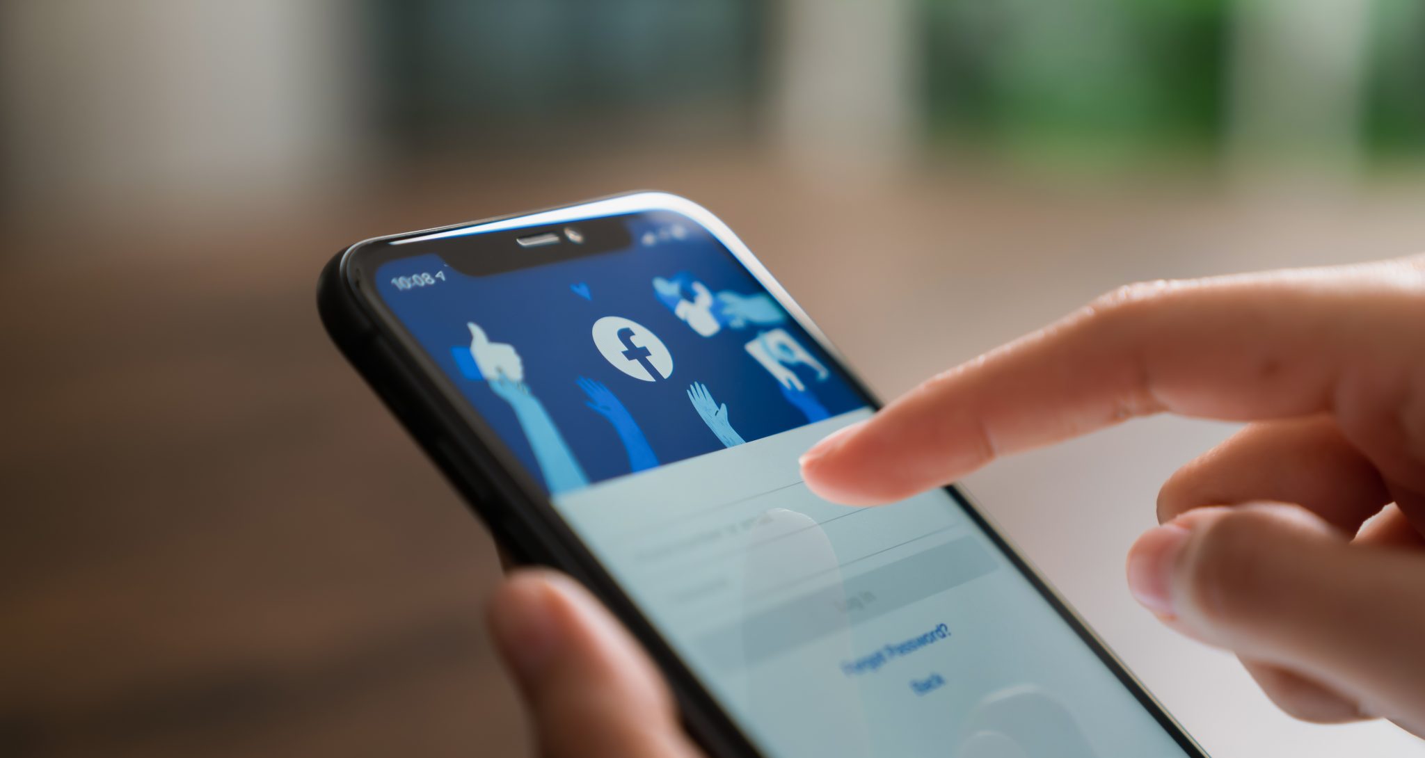 Bangkok, Thailand - September 23, 2020 : Hand is pressing the Facebook screen on apple iphone 11, Social media are using for information sharing and networking.