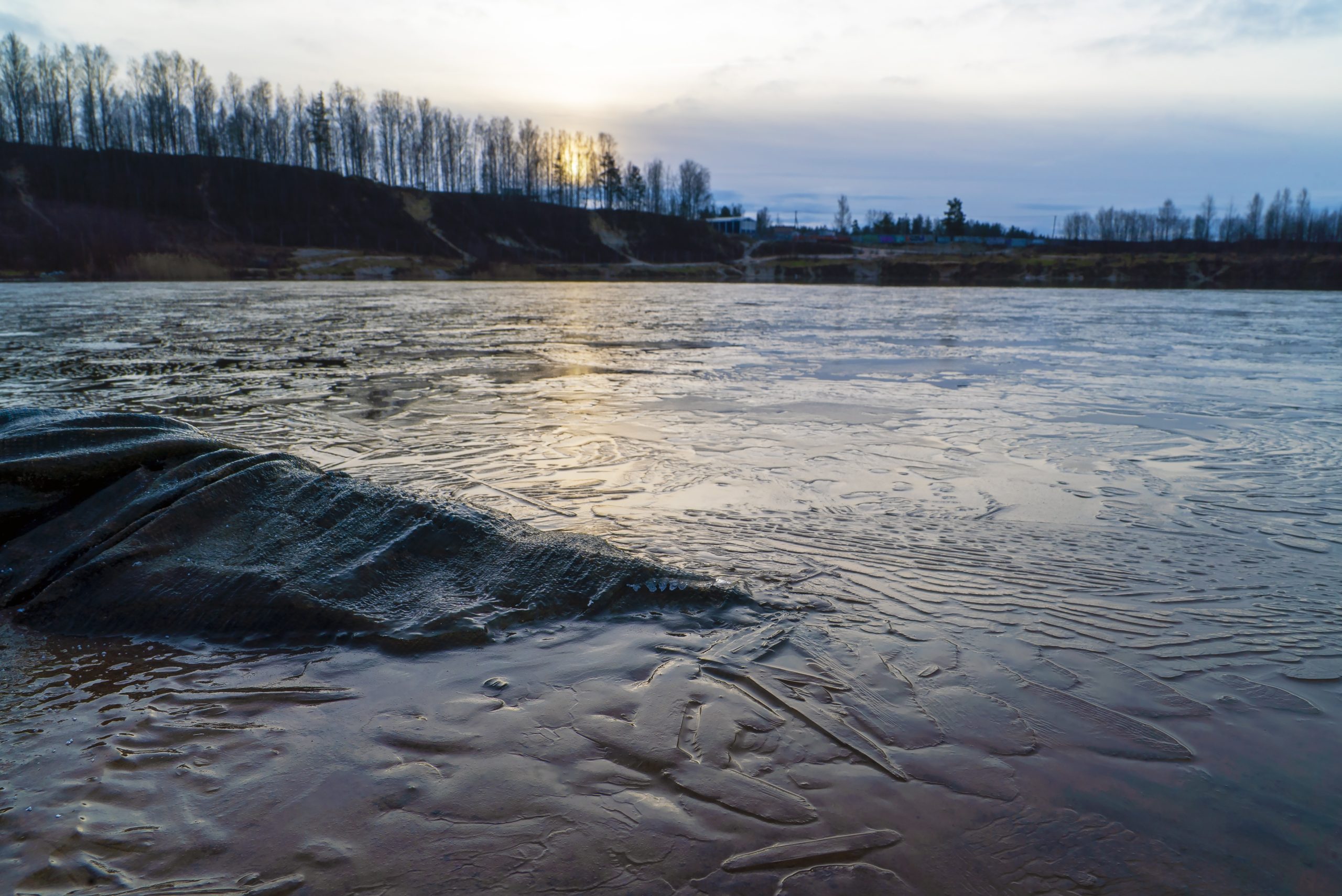 Thin ice on the water of a sand pit in late autumn at sunrise. Leningrad region, Vsevolozhsk